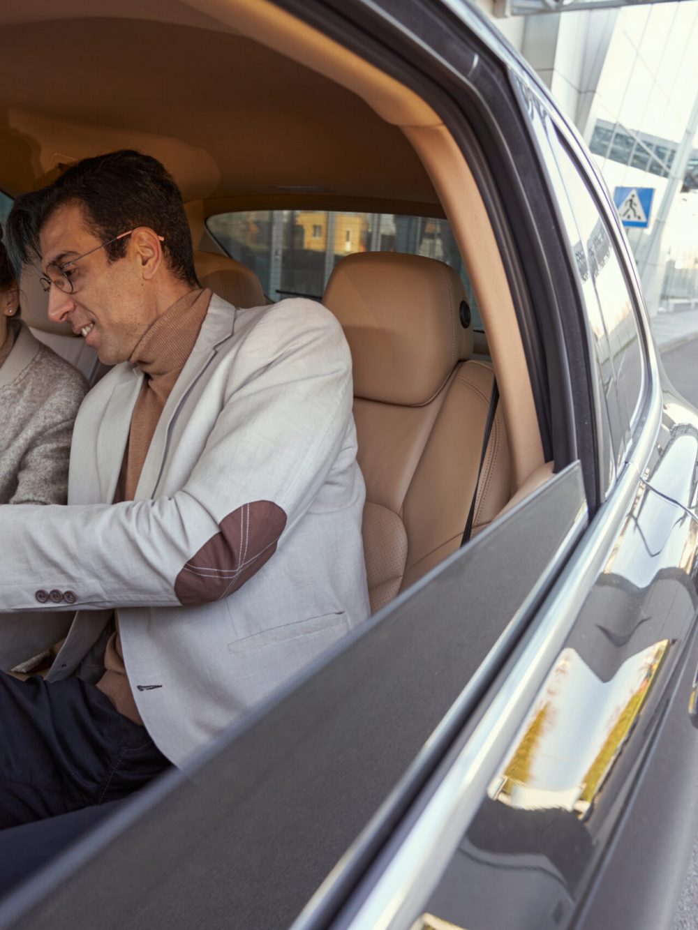 Woman holding hand of Caucasian man in back seat of car while he finishing phone call